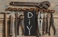 Flat lay with different carpentry tools set of hand tools and letters of DIY on a wooden background. Old rusty tools Royalty Free Stock Photo