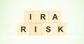 Letters ira and risk with wooden cubes on light green
