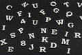 Letters of Latin alphabet on black background. Seamless black and white pattern of randomly placed letters