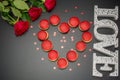 Letters Love on black background with red roses and tasty macaroon Royalty Free Stock Photo