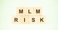 Letters mlm and word risk with wooden cubes on light green