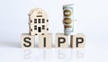 Letters sipp on wooden cubes on table with wooden house and dollar