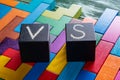 Letters VS on colorful wooden background with copy space. The concept of making choice. Black cubes with letters VS