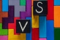 Letters VS on colorful wooden background with copy space. The concept of making choice. Black cubes with letters VS