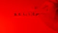 The letters of the words believe are eliminated to form the lie all illuminated by a red light