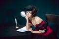 Young woman as Anna Karenina on dark blue background. Retro style, comparison of eras concept.