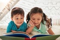 Letting their imagination and curiosity travel through books. two adorable young siblings reading a book together at Royalty Free Stock Photo