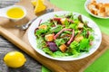 delicious fresh salad of salami and mixed lettuce leaves - baby spinach, arugula, chard in a white dish on the old wooden Royalty Free Stock Photo