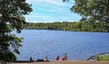 Beautiful idyllic dutch swimming lake with people sitting on pier, green forest