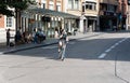 Leuven, Flemish Brabant - Belgium - Young student girl driving down a street with a bike, calling on her smartphone