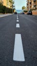 Level asphalted road with a dividing white stripes. The texture of the tarmac, top view.