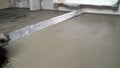 Leveling the floor with a long spatula. Builder levels a laid floor. Floor laying at home. The builder is laying concrete floor in