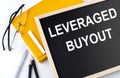 LEVERAGE BUYOUT text on blackboard with notepad , pen, pencil Royalty Free Stock Photo