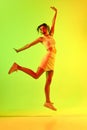 Portrait of emotive, a young girl wearing elegant costume jumping over gradient studio background in neon light Royalty Free Stock Photo