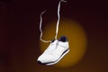 Levitating Shoes Concepts. Pair of New White Sneakers With Flying Shoelaces Placed Over Yellow Background With Circular Spotlight