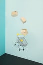 Levitating shopping cart and paper boxes on blue background. Safe online shopping on quarantine concept. Flying Empty