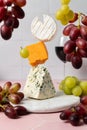 Levitating soft goat cheese, cheddar and blue stilton with red wine and grape Royalty Free Stock Photo