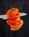 Levitation of fresh cut tomato. A knife cuts tomato in the air. 5 flying tomato slices isolated on a black background Royalty Free Stock Photo