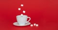Levitation of sugar cubes over a white mug with a saucer on a red isolated background. Levitation of objects.Minimalism or Royalty Free Stock Photo
