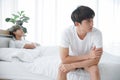 Lgbt Asian gay couple quarreling and irritated in bedroom. Stressed young man sitting at end of bed with arms crossed Royalty Free Stock Photo