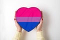 LGBT bisexual pride flag on a heart shape box in female hands. Pride symbol. Top view