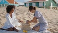 Lgbt couple enjoying picnic at beach houses sunny summer day. Happy girls rest