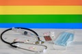 LGBT flag on the background of pills , stethoscop e an d medical mas k o n the table. The flag of sexual minorities and medical