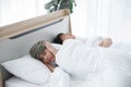 Lgbt gay couple having problems in bed. Young man with sullen face covering his ears and lying with boyfriend who snoring loudly Royalty Free Stock Photo