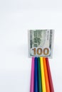 LGBT and Gay Pride rainbow colored pencils with a $100 bill against a white background. Equality and Diversity concept - image