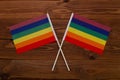 LGBT rainbow flag crossed with each other on a brown background with a wood texture. LGBTQ rights symbol banner in visual media.