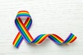 LGBT rainbow ribbon pride symbol. Stop homophobia. White wood background. Copy space for text.