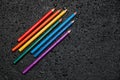 Rainbow color pencils on a black background with drops of water