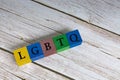 LGBTQ acronym on colorful wooden cubes against blue background.