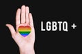 LGBTQ communities. Hand of a man with a rainbow flag on a black background