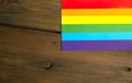 LGBTQ community flag on a wooden background. On the wooden table there is a symbol of LGBT freedom.