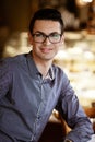 LGBTQ community lifestyle concept. Young homosexual man sits at the table in old-fashioned city cafe. Handsome smiling