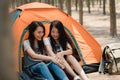 Lgbtq lesbian women couple camping or picnic together in forest, teenager female enjoy moment talking in front of their tent.