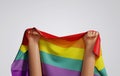 LGBTQ people raise their hands with a rainbow flag