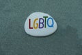 LGTBQ, creative logo carved and colored on a stone over green sand Royalty Free Stock Photo