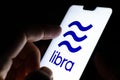 Libra digital currency logo on a smartphone and finger is about to touch it. Selective focus. Conceptual photo for Facebook Libra