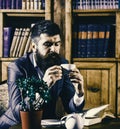 Librarian to the library. Oldfashioned man holds cup with tea. Aristocratic lifestyle concept. Royalty Free Stock Photo