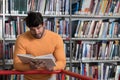 Happy Male Student Reading from Book in Library Royalty Free Stock Photo