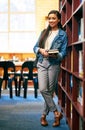 The library is a place to experience a wealth of knowledge. Portrait of a university student standing in the library at