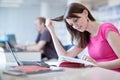 In the library - pretty female student with laptop and books Royalty Free Stock Photo