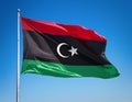 Libyan flag, solid green color, fluttering gently against a serene blue sky
