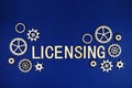 Licensing alphabet letters with gears element on navy blue background Royalty Free Stock Photo