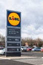 Lidl sign at entrance to customer car park. Displays opening hours and facilities