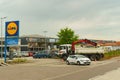 Lidl store sign with brand logo. Parking and other shops nearby.