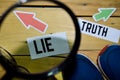 Lie or Truth opposite direction signs in magnifying with sneakers and eyeglasses on wooden Royalty Free Stock Photo