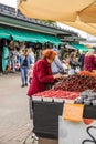 Liepaja, Latvia- July 7, 2023: Old lady in red top and ginger hair is buying cherries in local street market stand